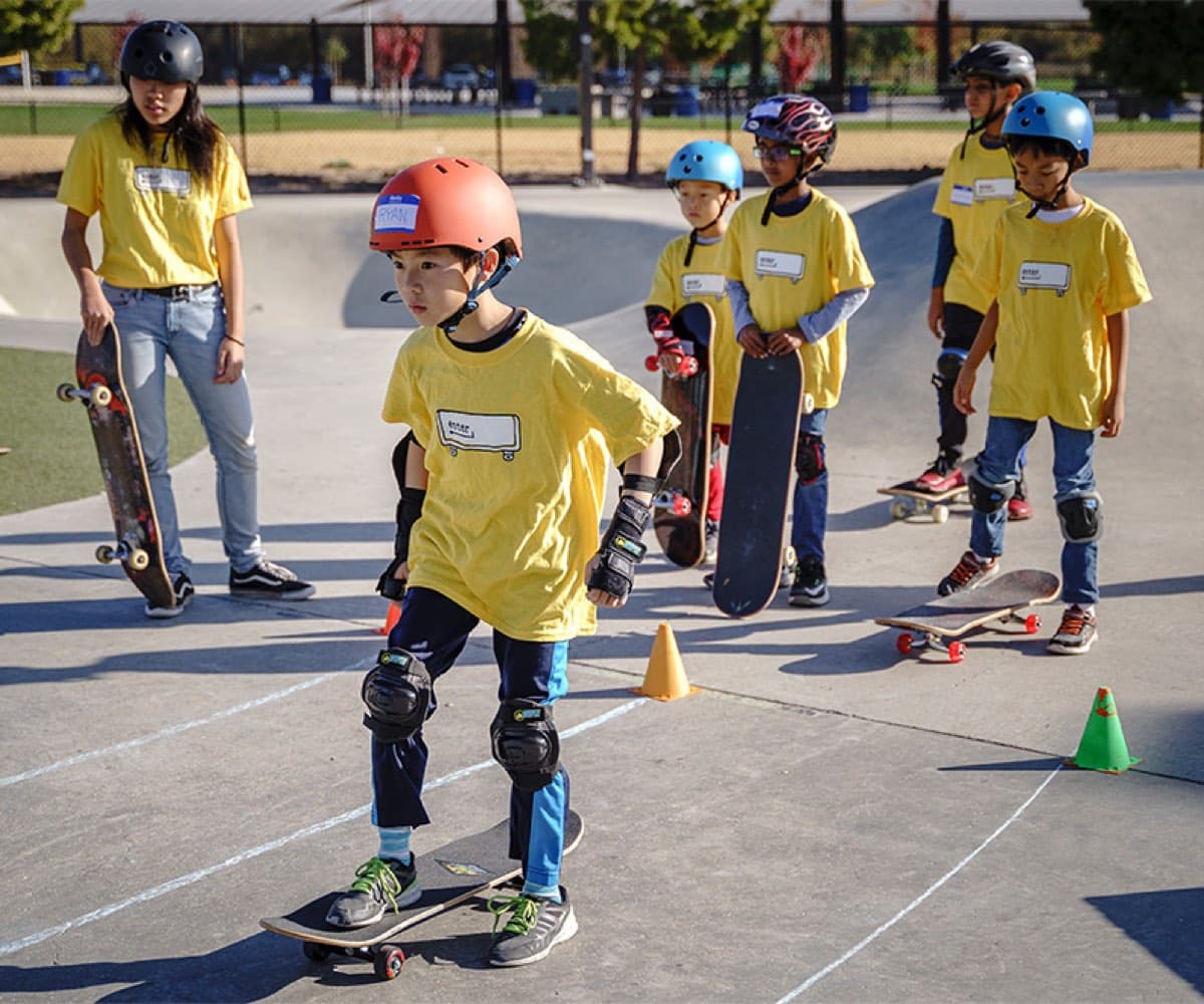 Enter campers in yellow program shirts lined up with their boards at Fremont Skate Park